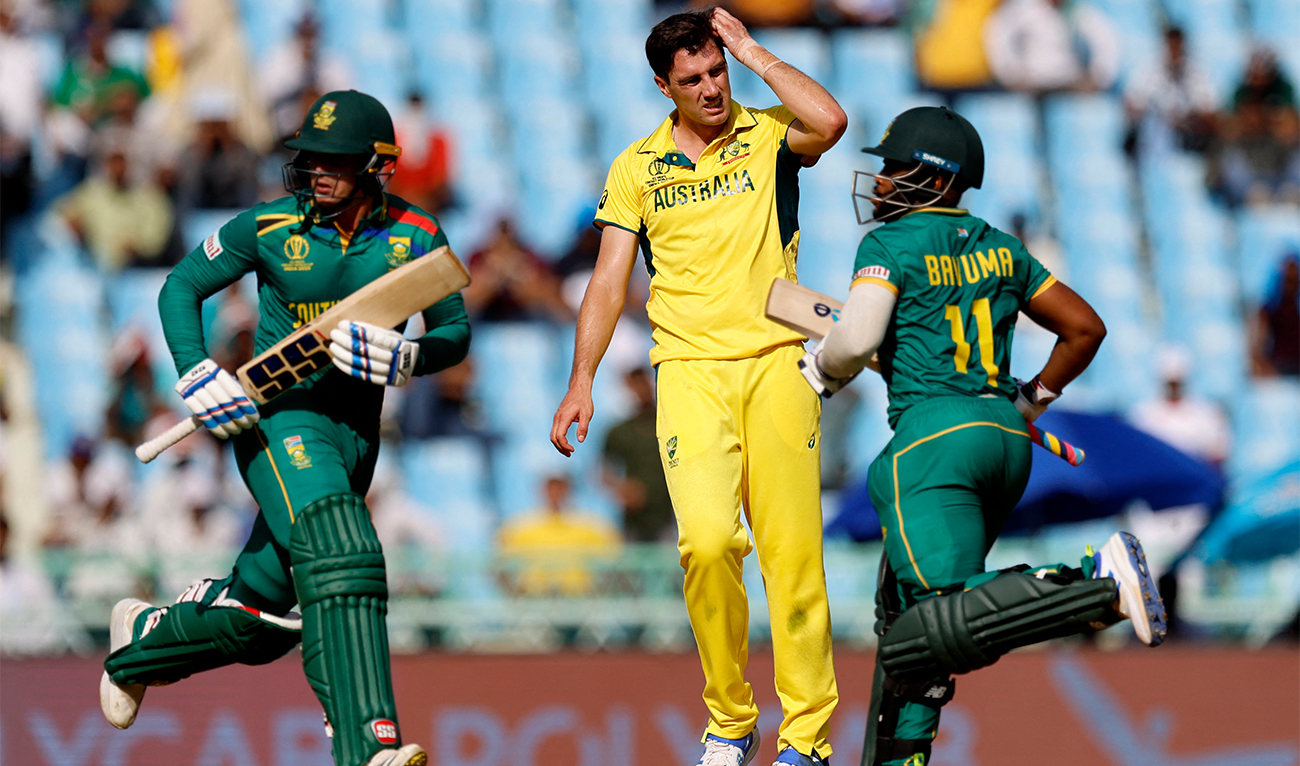 South Africa's Quinton de Kock and Temba Bavuma run between wickets as Australia's Pat Cummins (in yellow) reacts during a Cricket World Cup contest at Bharat Ratna Shri Atal Bihari Vajpayee Ekana Cricket Stadium in Lucknow, India, on October 12, 2023. (REUTERS)