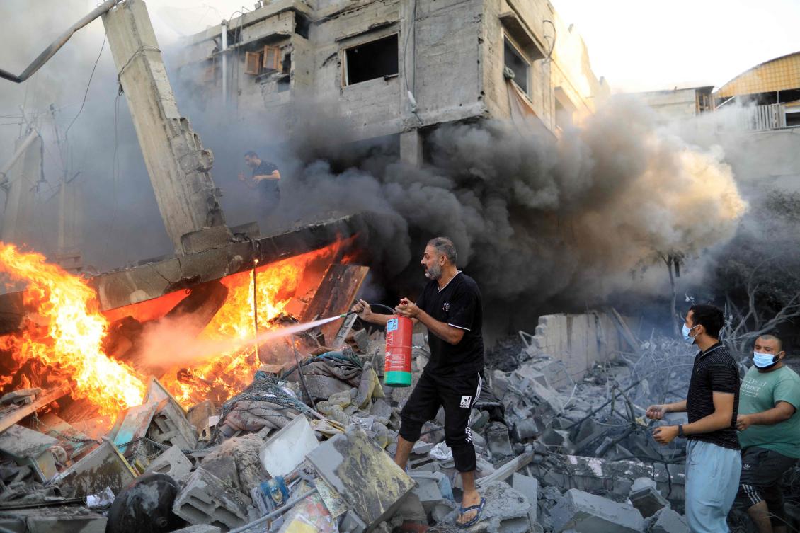 A Palestinian man uses a fire extinguisher to douse a fire following an Israeli strike, in Khan Yunis in the southern Gaza Strip on Oct. 14, 2023. (AFP)