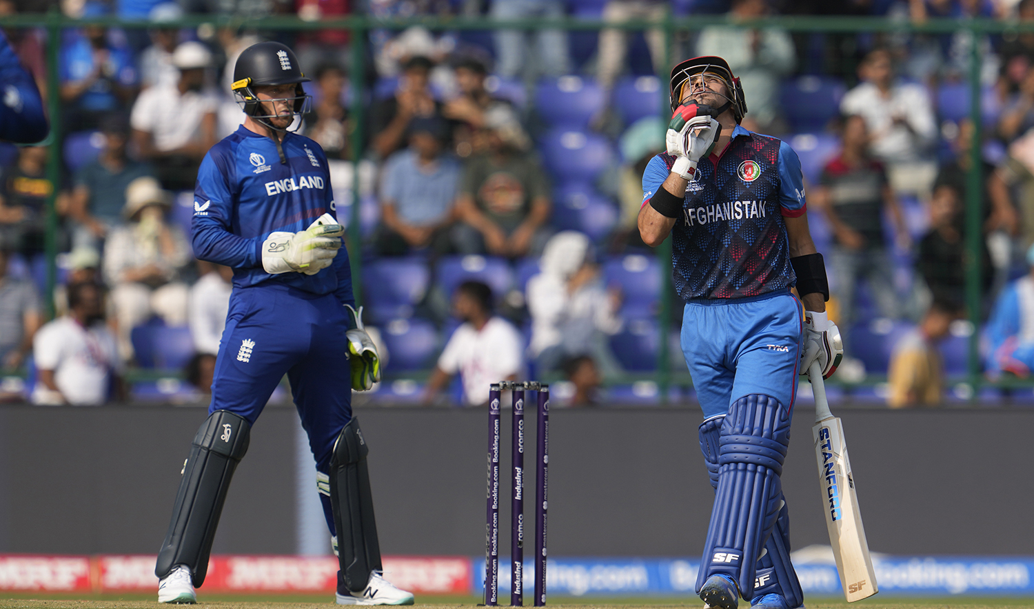 Afghanistan's Rahmanullah Gurbaz celebrates his fifty runs as England's captain Jos Butler watches during the ICC Men's Cricket World Cup match between Afghanistan and England in New Delhi, India, on October 15, 2023. (AP)