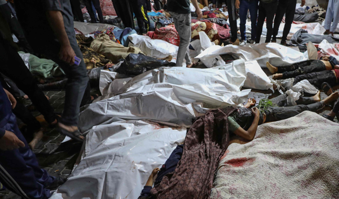 People gather around bodies of Palestinians killed in Israeli airstrikes on the Ahli Arab hospital in central Gaza after they were transported to Al-Shifa hopsital, on October 17, 2023. (AFP)