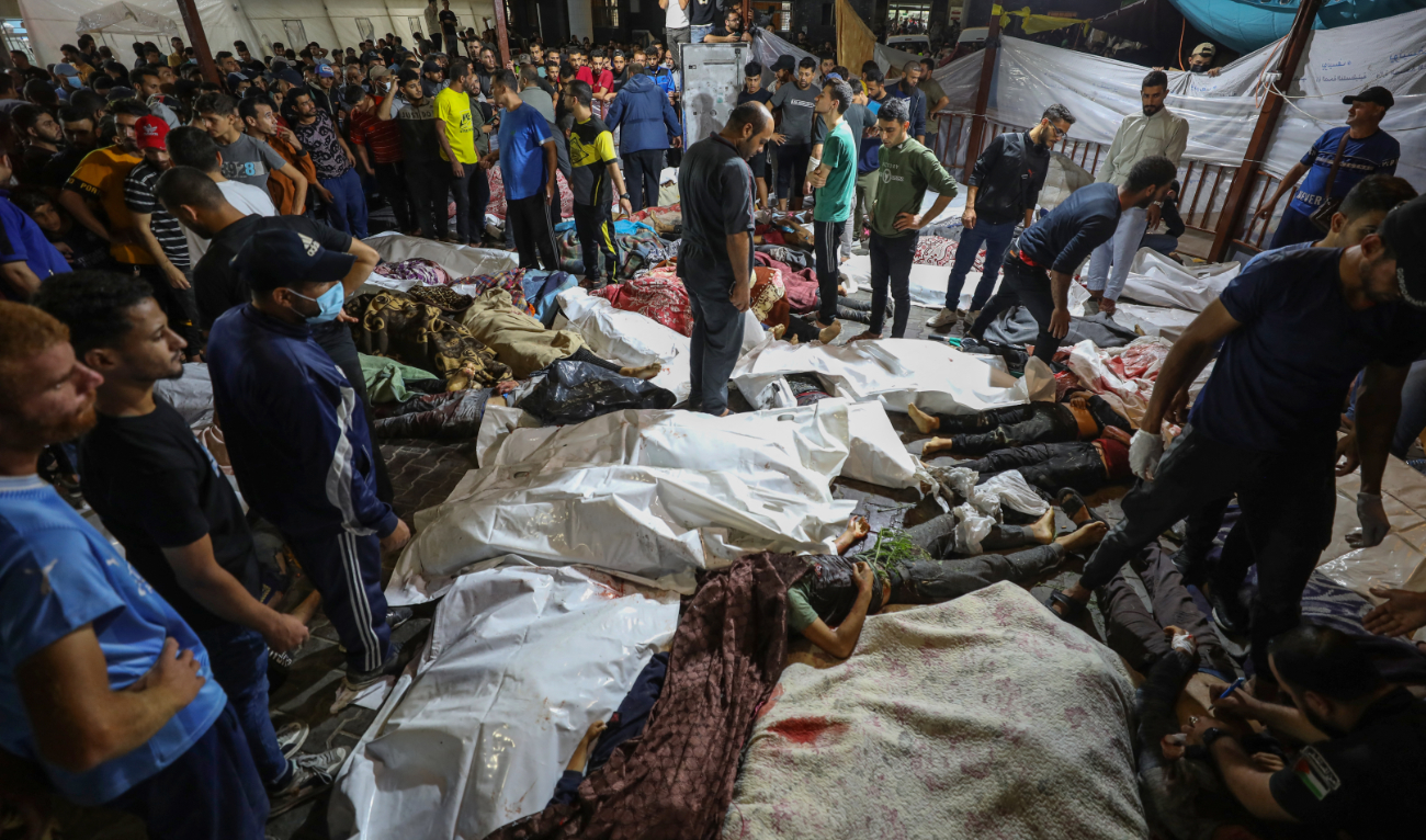 People gather around bodies of Palestinians killed in a strike on the Ahli Arab hospital in central Gaza after they were transported to Al-Shifa hospital, on October 17, 2023. (AFP)