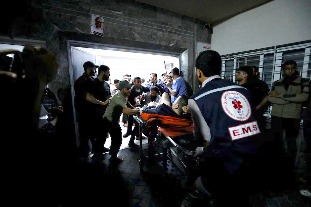 An injured person is assisted at the Shifa Hospital after hundreds of Palestinians were killed in an Israeli strike on Al-Ahli hospital in Gaza on Oct. 17, 2023. (AFP)