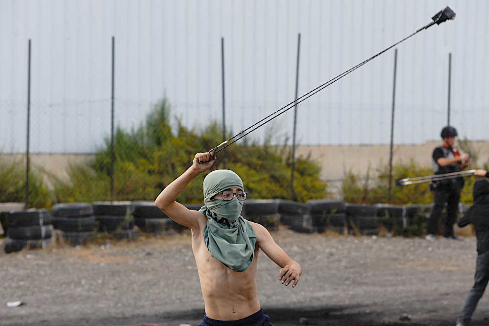 A Palestinian child uses a sling to hurl stones during clashes with Israeli forces near Ramallah in the Israeli-occupied West Bank. (Reuters)