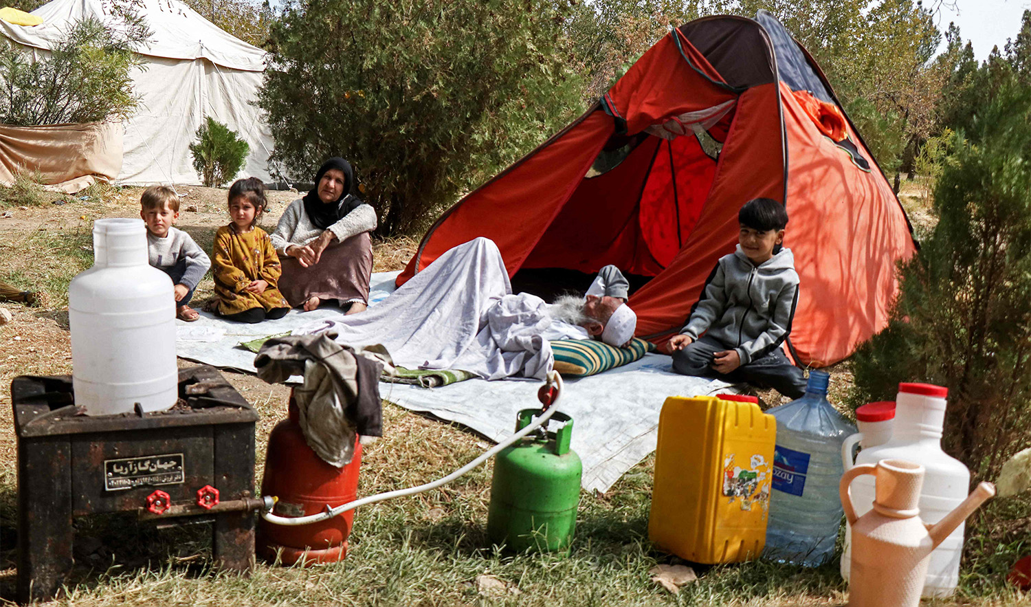 A family rests outside their makeshift tent set-up after earthquake at a park in Herat, Afghanistan on October 17, 2023. (AFP)