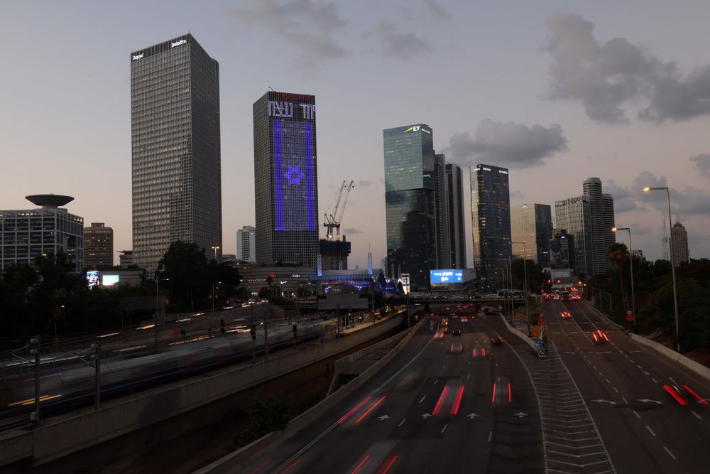 The Israeli national flag is projected against the facade of a building along a highway in Tel Aviv. (AFP)