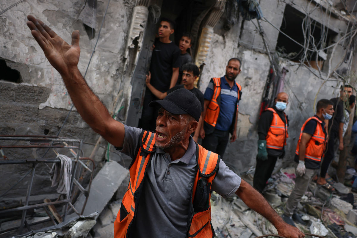 A rescuer reacts during the search for victims or survivors in a car covered by the rubble of a house destroyed in an Israeli strike in Gaza. (AFP)