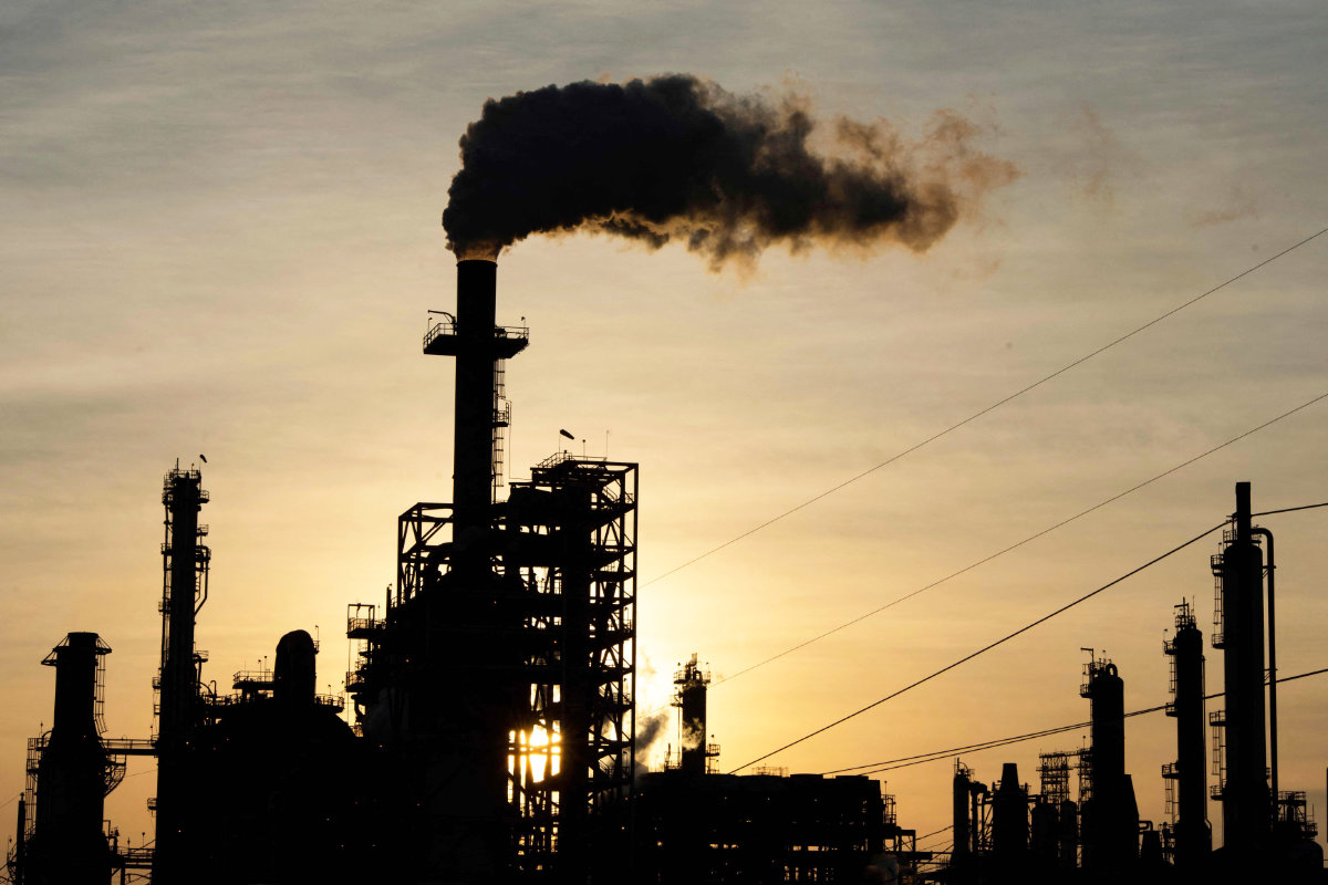 The sun sets behind smoke rising from the LyondellBasell-Houston Refining plant in Houston, Texas. Global oil prices eased on Monday as aid convoys started to arrive in the Gaza Strip over the weekend. (AFP)