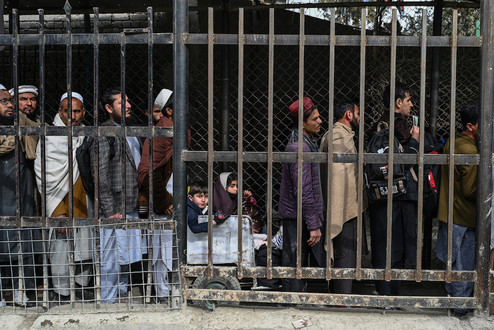 Above, Afghan men stand in queue inside a fenced corridor as they wait to cross into Pakistan at the zero-point Torkham border crossing between Afghanistan and Pakistan in Nangarhar. (AFP file photo)