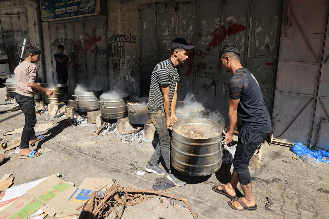 People cook on firewood, amid shortages of fuel and gas, to provide food for displaced Palestinians amid Israeli strikes in Khan Yunis, in the southern Gaza Strip October 15, 2023. (File/AFP)