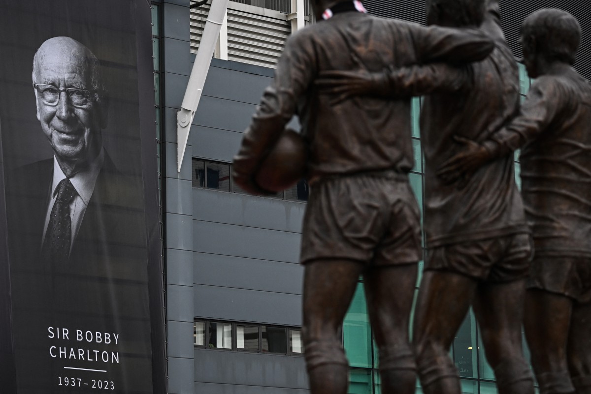 Tributes and flowers are pictured at the base of the 'United Trinity' sculpture, depicting former Manchester United players George Best, Denis Law and Bobby Charlton, following the death of Bobby Charlton, outside of Old Trafford football stadium in Manchester (AFP)