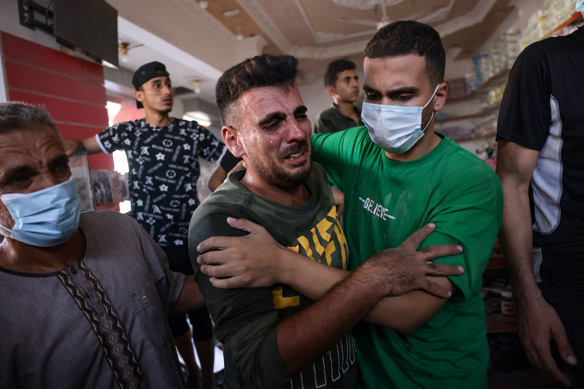 People react following an Israeli strike that hit a supermarket in the Rafah refugee camp in the southern Gaza. (File/AFP)