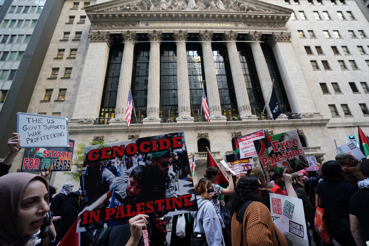 Protesters hold signs and flags during the "Flood Wall Street for Gaza" rally outside the New York Stock Exchange (AFP)