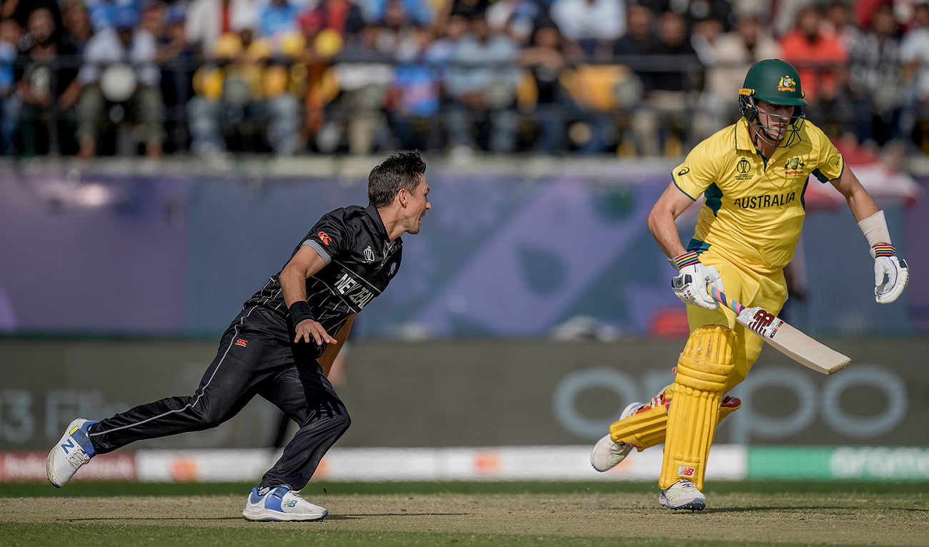 New Zealand's Trent Boult (L) runs to field the ball as Australia's captain Pat Cummins run between the wickets during the ICC Men's Cricket World Cup match between Australia and New Zealand in Dharamshala, India, Saturday, Oct. 28, 2023. (AP)