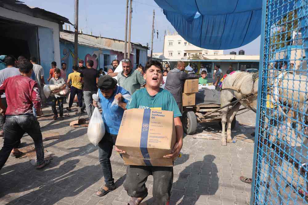 Palestinians storm a UN-run aid supply center, that distributes food to displaced families. (AFP)