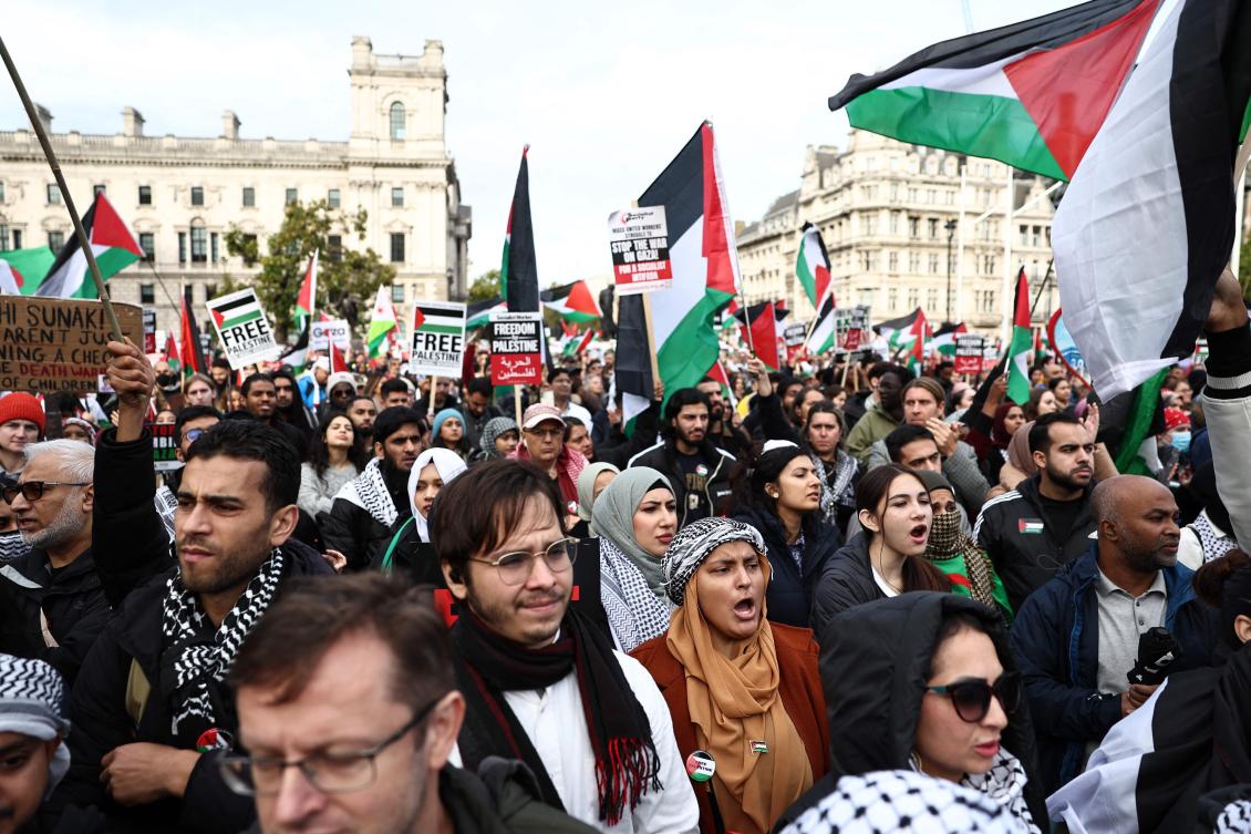 People hold up placards and wave Palestinian flags in Parliament Square after taking part in a ‘March For Palestine’ in London on October 28, 2023, to call for a cease-fire in the conflict between Israel and Hamas. (AFP)