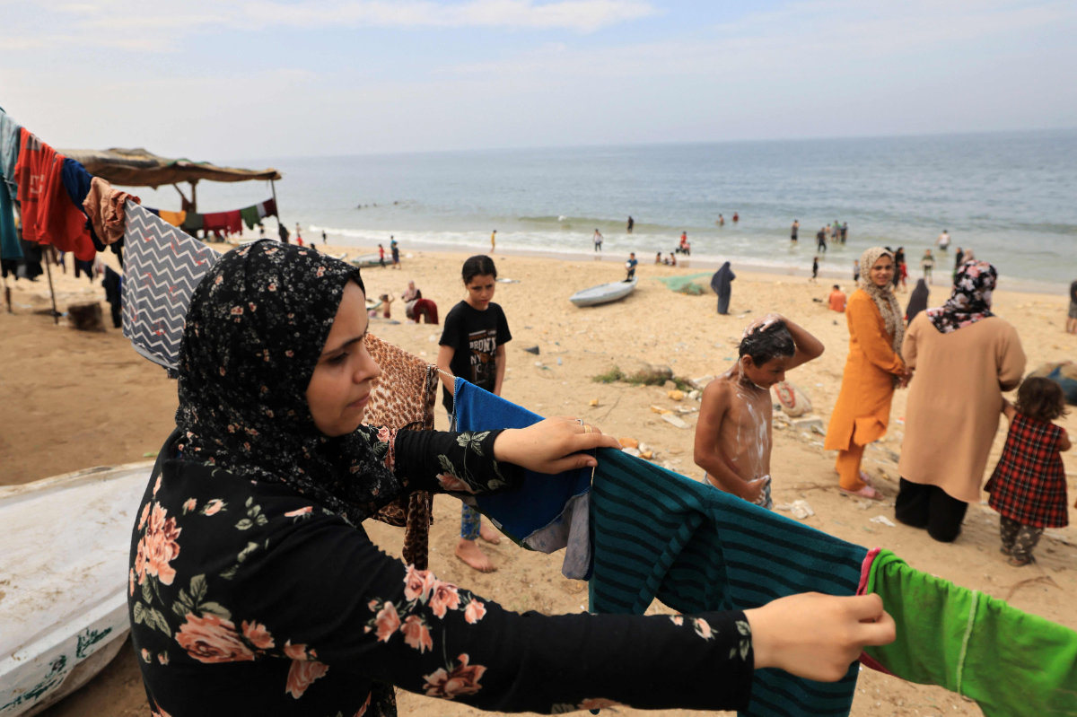 A Palestinian woman hangs laundry washed using sea water due to the lack of fresh water and electricity, along the beach in Deir el-Balah in the southern Gaza Strip on October 29, 2023, amid another invasion by Israeli forces. (AFP)