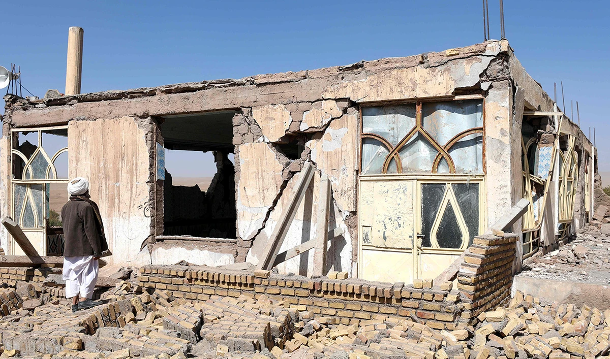 An Afghan man stands near a damaged house after the earthquakes in Sarbuland village, Zendeh Jan district of Herat province on October 8, 2023. (AFP)