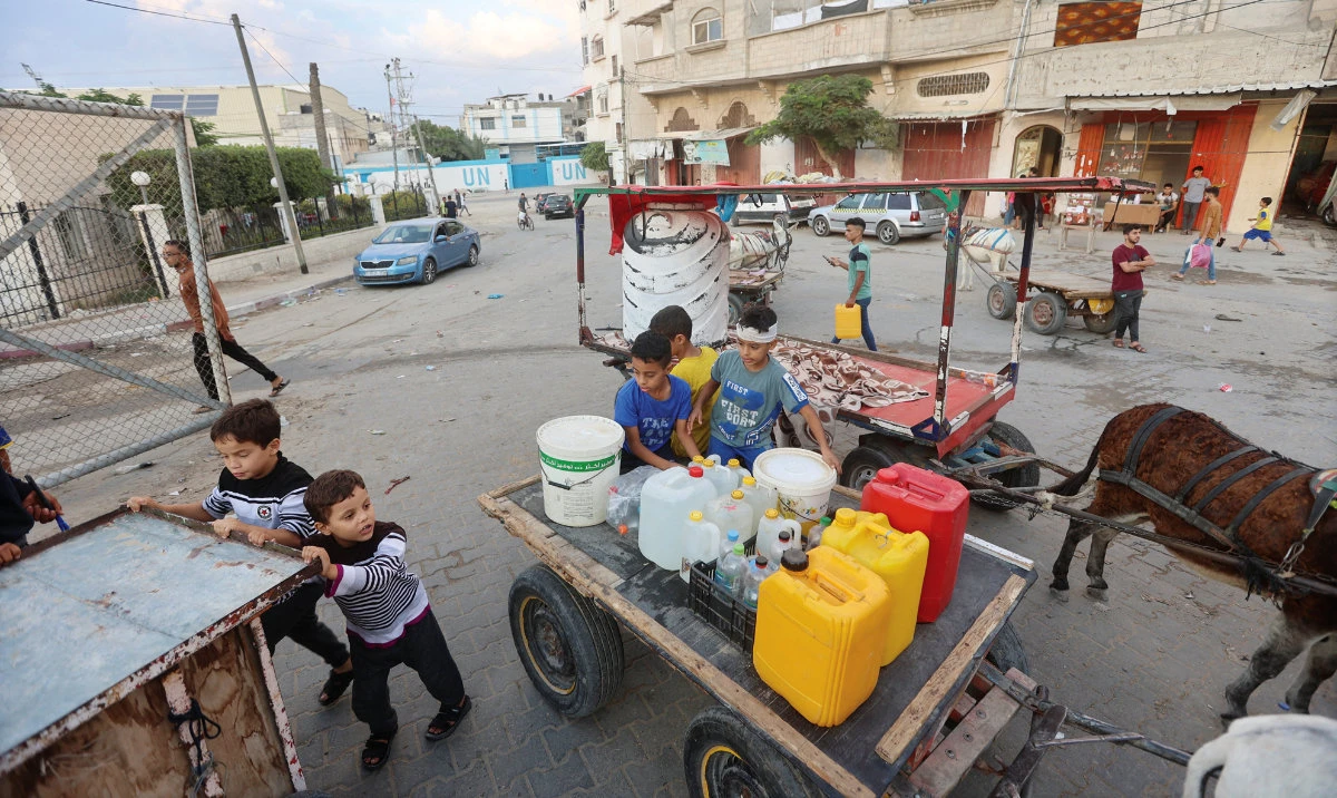 Children collect water in Khan Younis in the southern Gaza Strip on Saturday. Drinking water was in short supply amid an unrelenting bombardment. (Reuters)