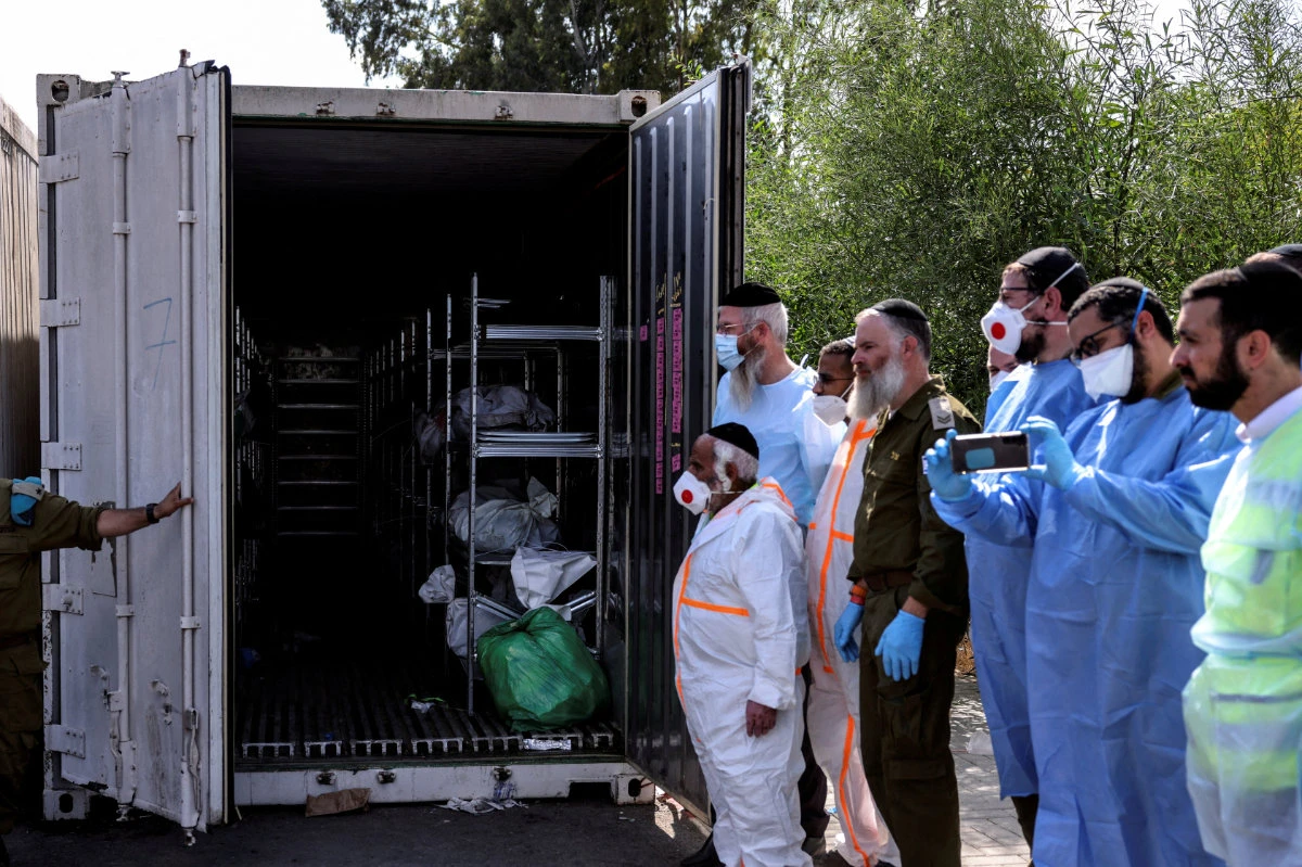 Israeli workers and military officers stand by a container with bodies of dead people in Ramla on October 13, 2023. The victims were some of hundreds killed in last week's storming of Israel by Hamas gunmen from the Gaza Strip. (REUTERS)