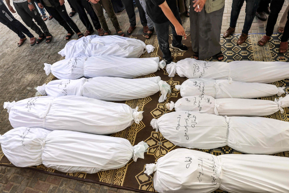 Mourners pray before the wrapped bodies of Palestinian victims who were killed in an Israeli air strike during their funeral in Rafah in the southern Gaza Strip on October 13, 2023. (AFP)