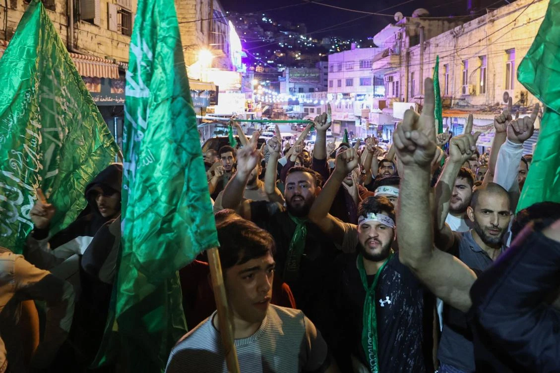 Palestinians lift Hamas movement flags as they protest in Nablus city in the occupied West Bank following an Israeli airstrike on a Gaza hospital compound killing hundreds on Oct. 17, 2023. (AFP)