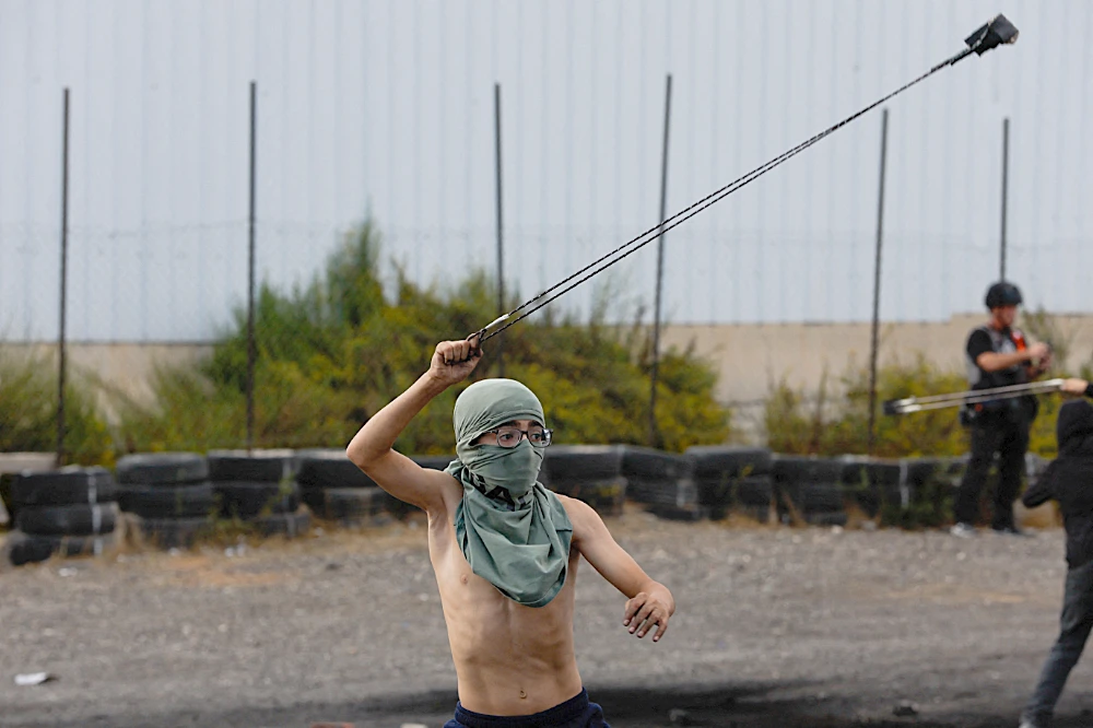 A Palestinian child uses a sling to hurl stones during clashes with Israeli forces near Ramallah in the Israeli-occupied West Bank. (Reuters)