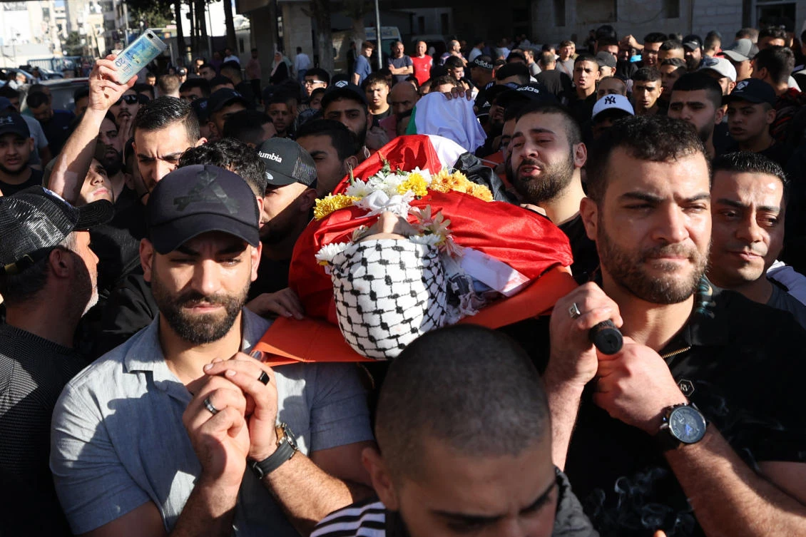 Mourners carry the body of Palestinian Ahmad Mutair, killed amid clashes with Israeli troops, from hospital to a cemetery in the occupied West Bank during his funeral procession at the Qalandia refugee camp on October 25, 2023. Violence in the West Bank continues as thousands of civilians, both Palestinians and Israelis, have died since October 7, 2023, after Palestinian Hamas militants based in the Gaza Strip entered southern Israel in an unprecedented attack triggering a war declared by Israel on Hamas with retaliatory bombings on Gaza. (Photo by Jaafar ASHTIYEH / AFP)