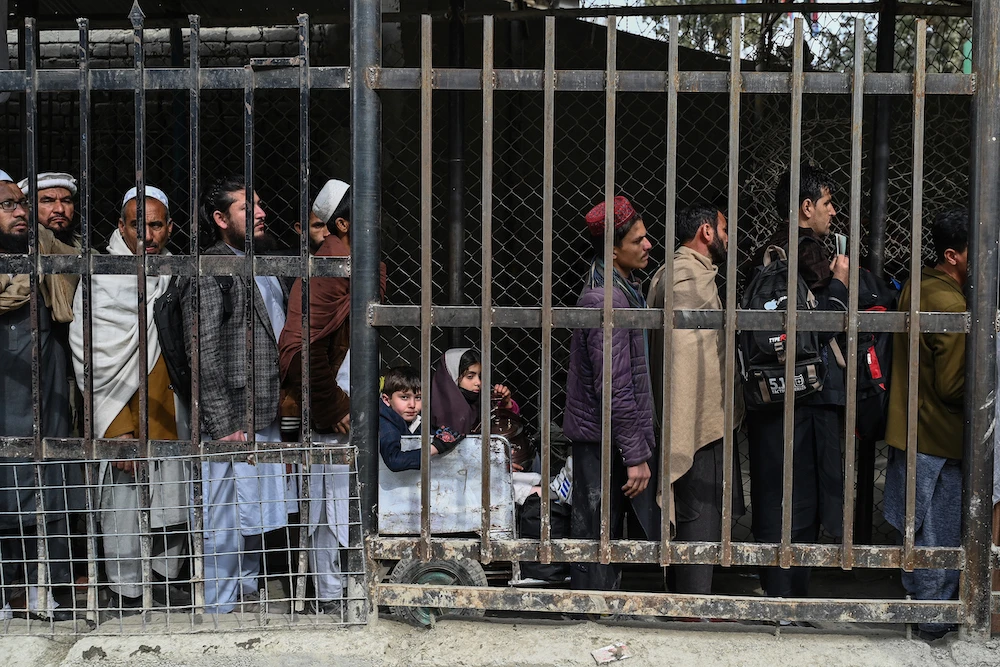 Above, Afghan men stand in queue inside a fenced corridor as they wait to cross into Pakistan at the zero-point Torkham border crossing between Afghanistan and Pakistan in Nangarhar. (AFP file photo)