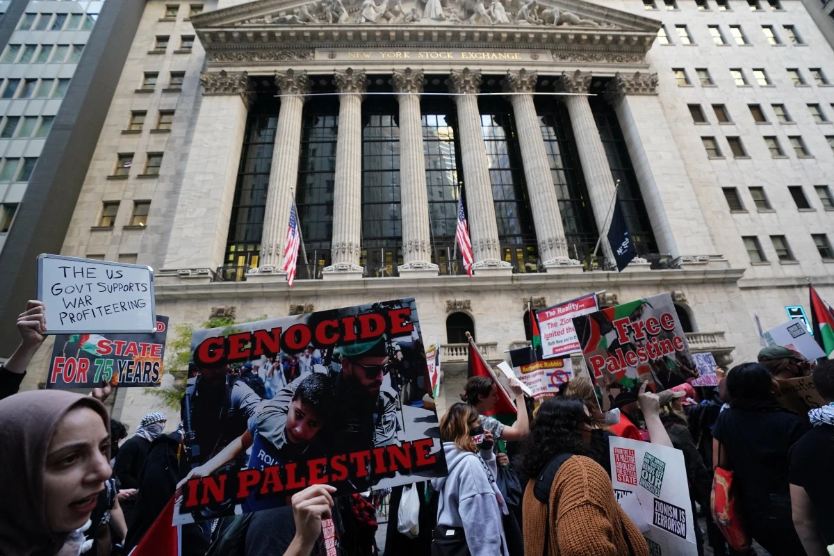 Protesters hold signs and flags during the "Flood Wall Street for Gaza" rally outside the New York Stock Exchange (AFP)