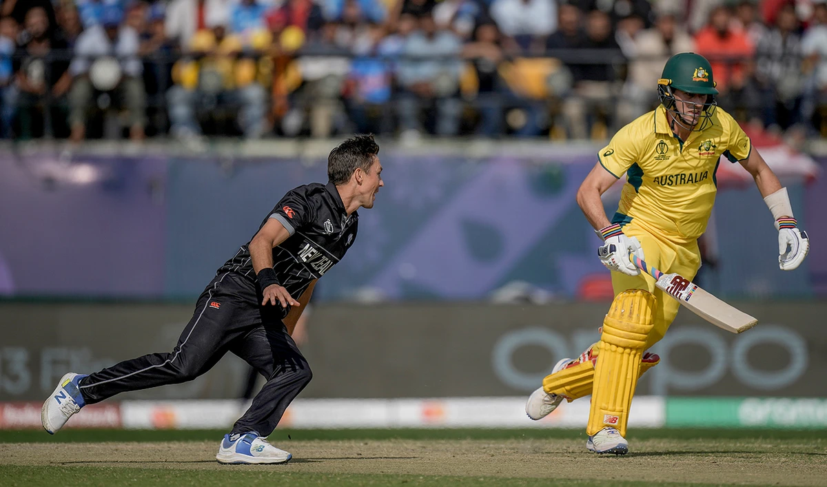 New Zealand's Trent Boult (L) runs to field the ball as Australia's captain Pat Cummins run between the wickets during the ICC Men's Cricket World Cup match between Australia and New Zealand in Dharamshala, India, Saturday, Oct. 28, 2023. (AP)