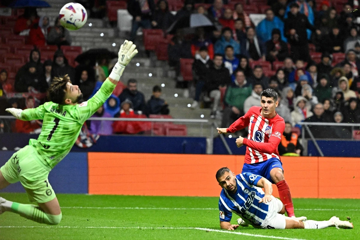 Atletico Madrid's Spanish forward Alvaro Morata (R TOP) scores his team's second goal despite being tackled by Alaves' Serbian defender Aleksandar Sedlar (BOTTOM) during their Spanish league football match at the Metropolitano stadium in Madrid on Sunday. (AFP)