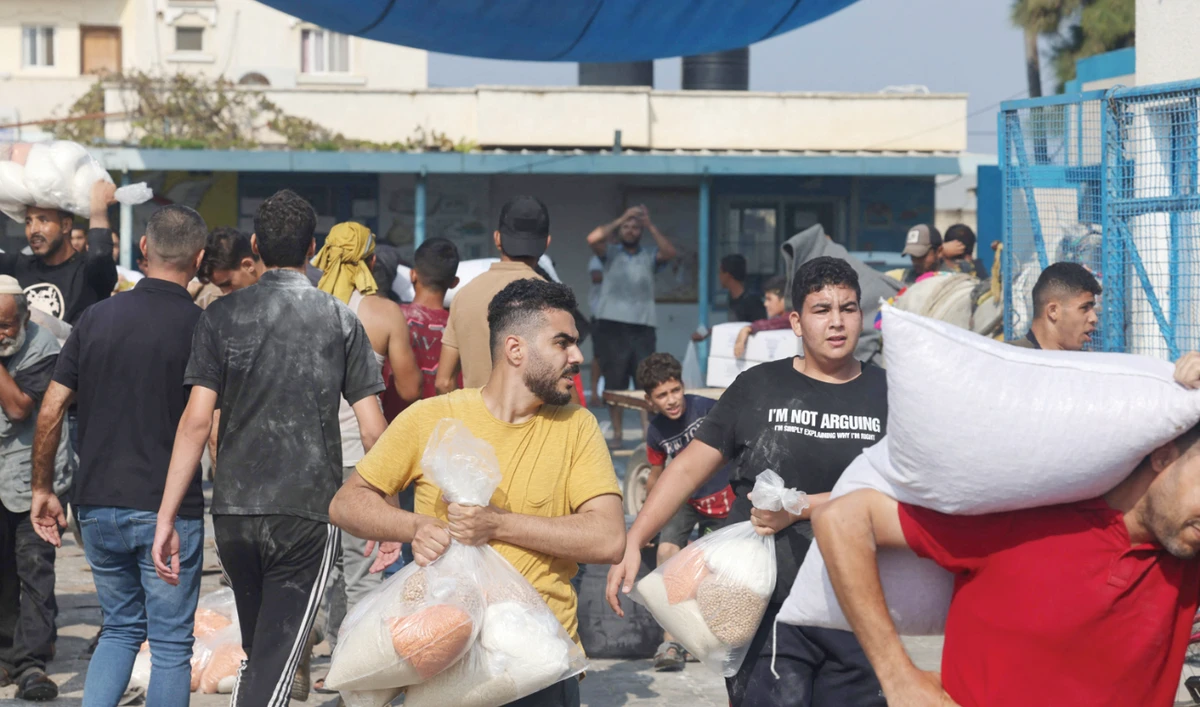 Palestinians collect bags of dried pulses from a UN-run aid supply center recently. (AFP)