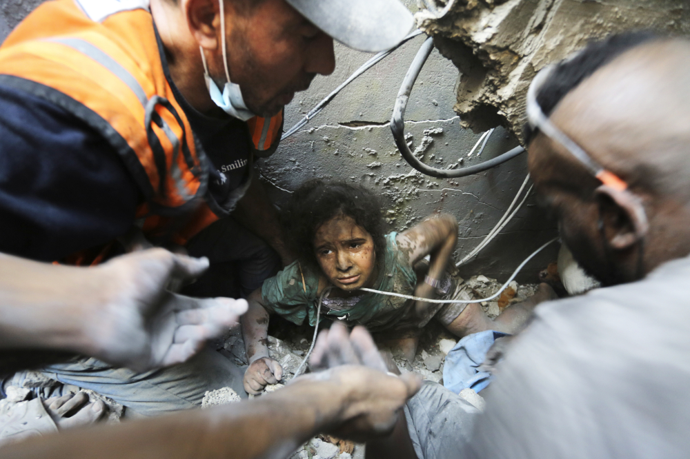 Palestinians try to pull a girl out of the rubble of a building that was destroyed by Israeli airstrikes in Jabaliya refugee camp, northern Gaza Strip. (AP)