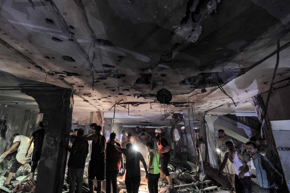 Rescuers search the home of Palestine TV journalist Mohamed Abu Hatab, who was killed along with family members. (AFP)