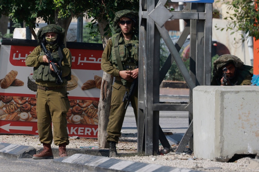 Israeli soldiers takes position along the road between the West Bank cities of Nablus and Tulkarem. (AFP)