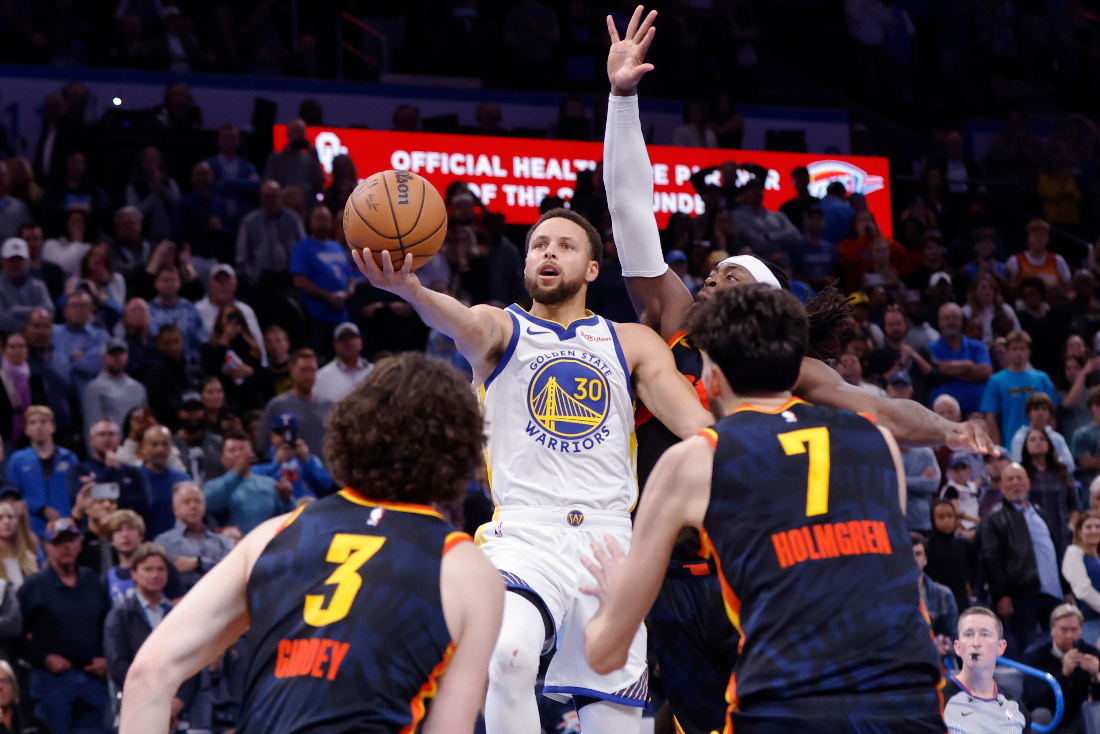 Golden State Warriors guard Stephen Curry hits a layup, scoring the winning basket in the final second, as Oklahoma City Thunder guard Josh Giddey (3), forward Chet Holmgren (7) and guard Luguentz Dort, back right, defend during an NBA in-season tournament game. (AP)
