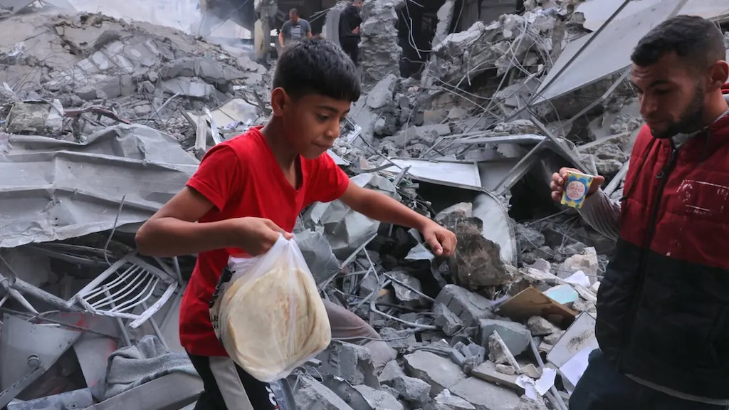 A Palestinian youth carries bread amid the rubble of the city center of Khan Yunis in the southern Gaza Strip following Israeli shelling on October 10, 2023. (File/AFP)