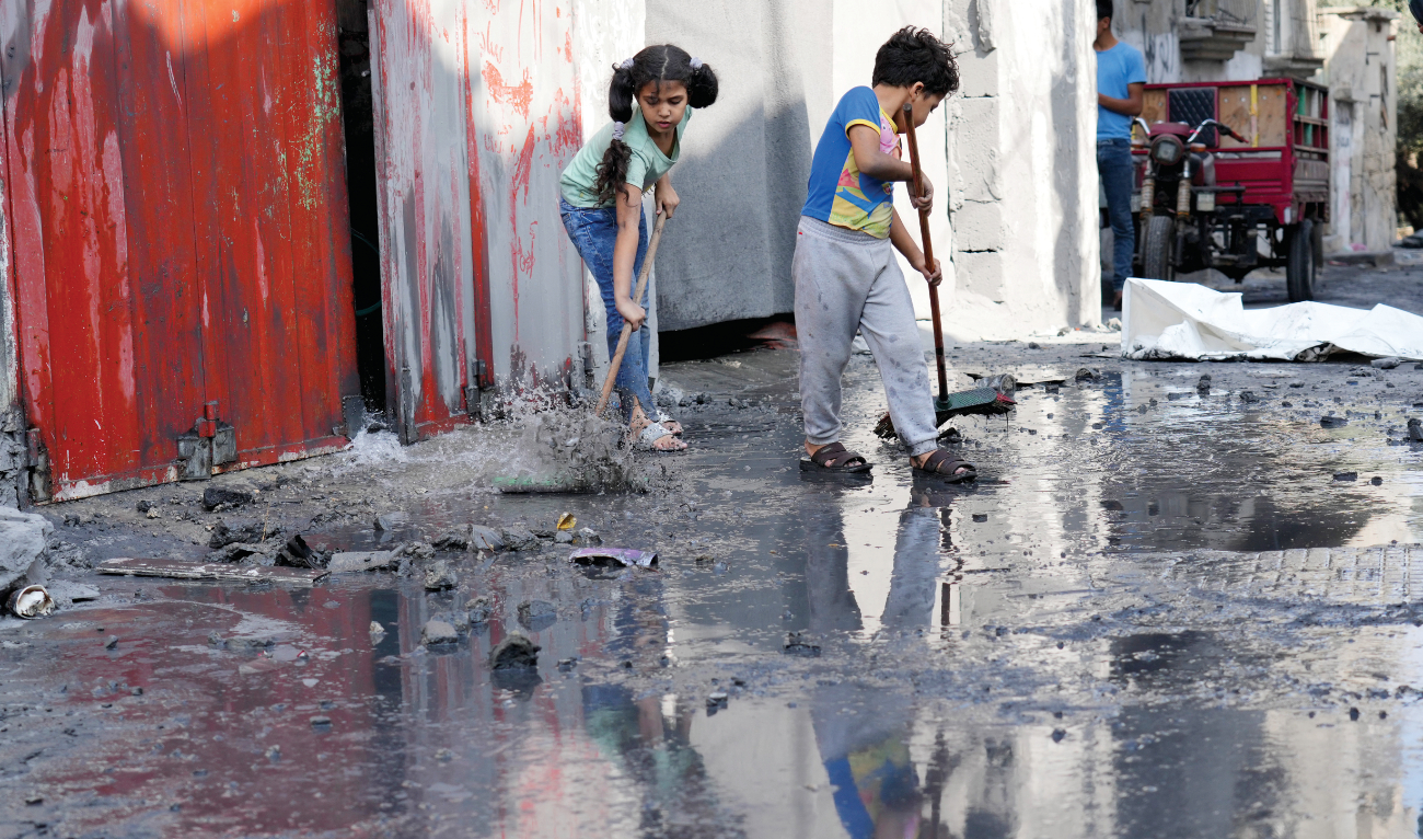Palestinian children mop outside their home after an Israeli bombardment in the Maghazi refugee camp in the Gaza Strip. (AP)