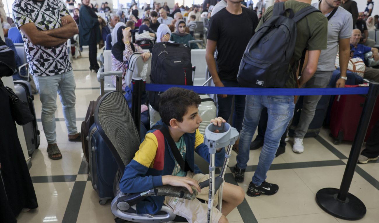 Palestinian dual nationals and foreigners wait to cross the Rafah border crossing with Egypt, in the southern Gaza Strip, on November 7, 2023. (AFP)