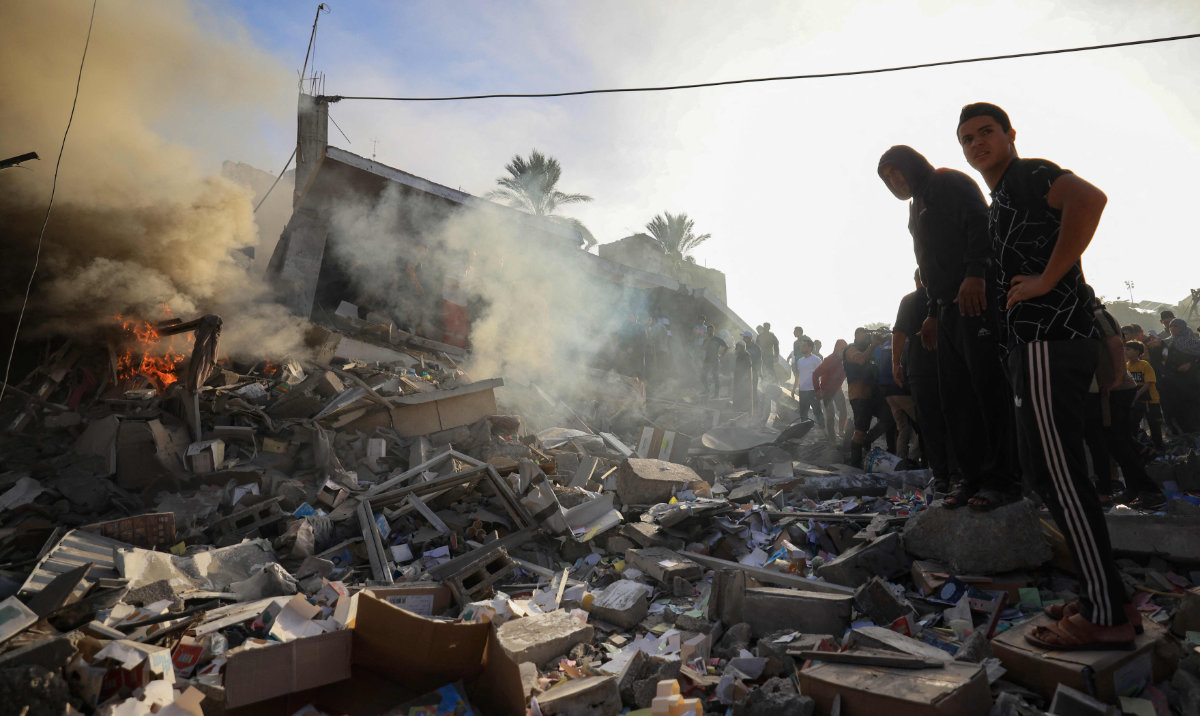 Palestinians stand above debris after Israeli bombardment in Khan Yunis in the southern Gaza Strip on November 7, 2023, amid continuing battles between Israel and the Palestinian militant group Hamas. (AFP)
