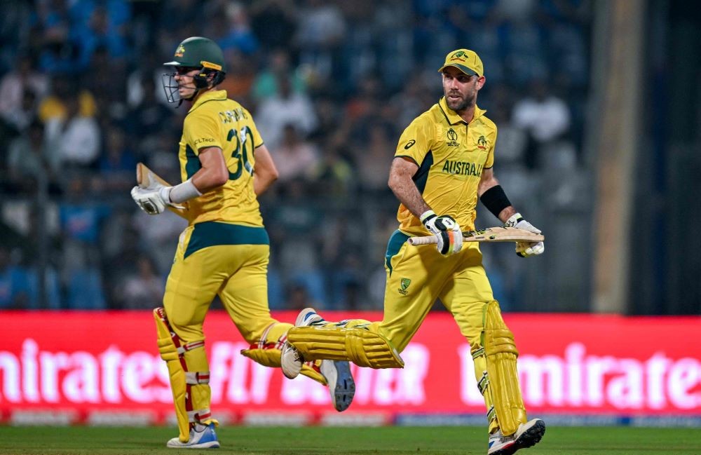 Australia’s Glenn Maxwell and Pat Cummins, left, run between the wickets during the 2023 ICC Men’s Cricket World Cup ODI match against Afghanistan, Wankhede Stadium, Mumbai, Nov. 7, 2023. (AFP)