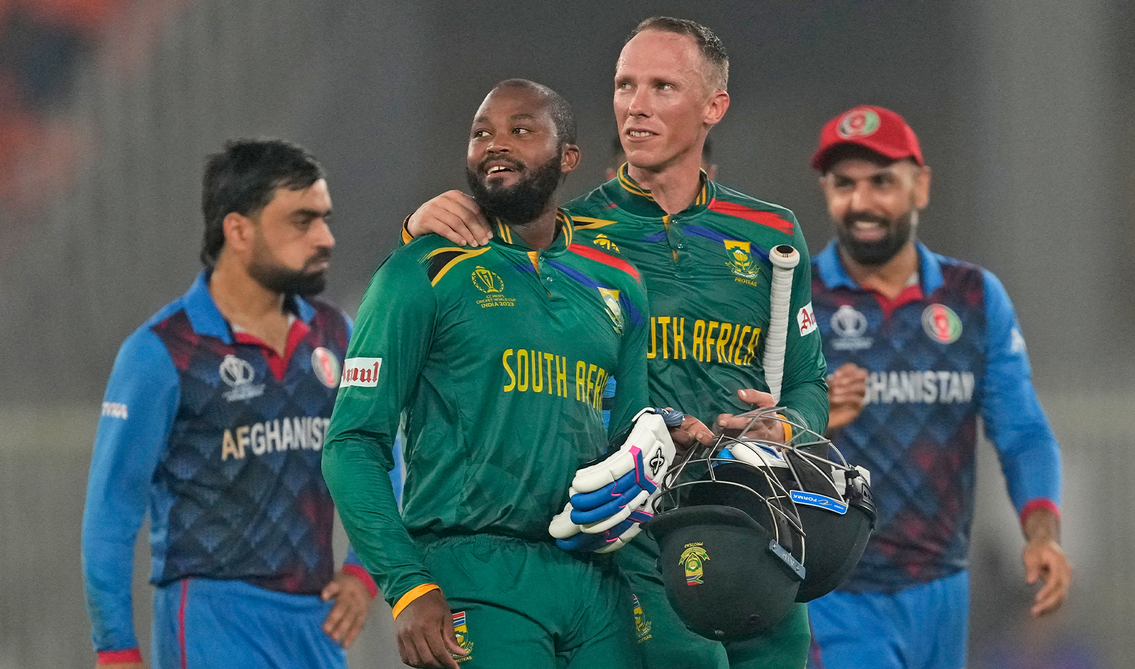 South Africa's Andile Phehlukwayo, second left, leaves the ground with teammate Rassi Van Der Dussen after South Africa won the ICC Men's Cricket World Cup match against Afghanistan in Ahmedabad, India, on November 10, 2023. (AP)