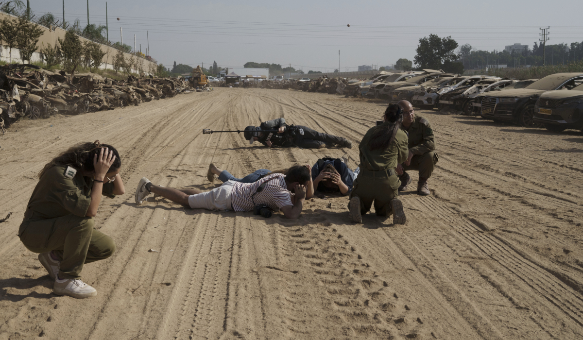 Israeli soldiers and journalists take cover as a siren warns of incoming rockets fired from the Gaza Strip in an area where hundreds of destroyed vehicles are kept that were damaged in the bloody Oct. 7 cross-border attack by Hamas militants, in which hundreds of people were killed and 240 others were taken hostage, outside the town of Netivot, southern Israel, Sunday, Nov. 5, 2023. (AP)