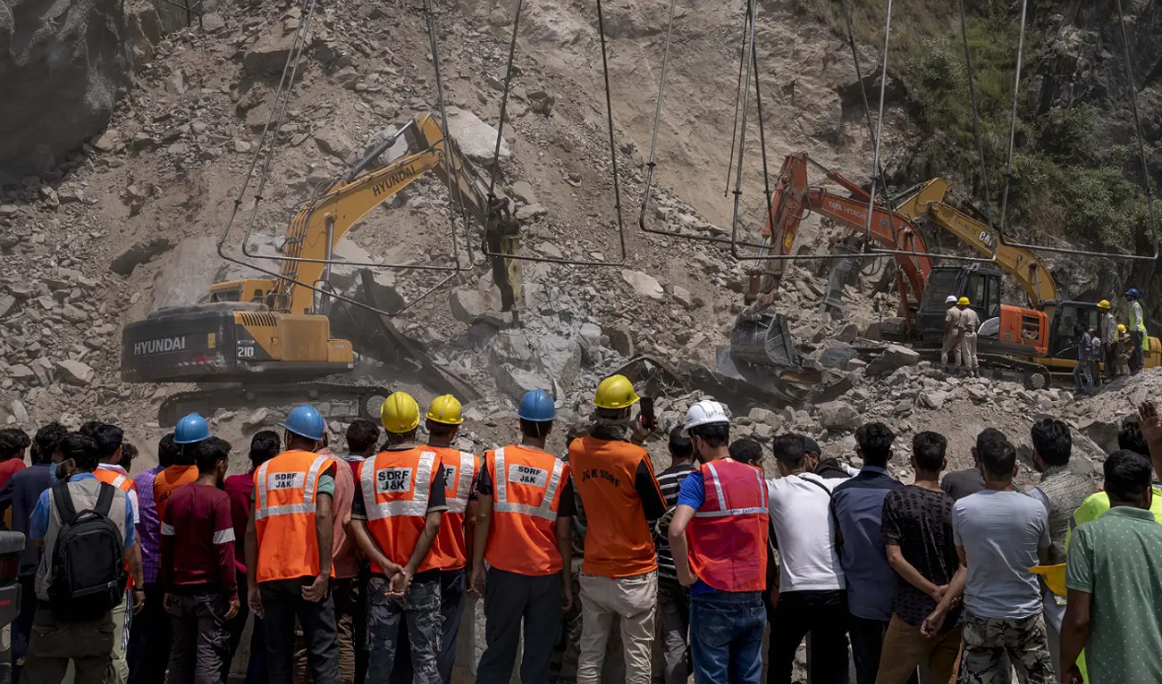 In this file photo, taken on May 20, 2022, rescue workers watch from a distance as earth movers dig through rubble of a collapsed tunnel in Ramban district of Srinagar. (AP/File)