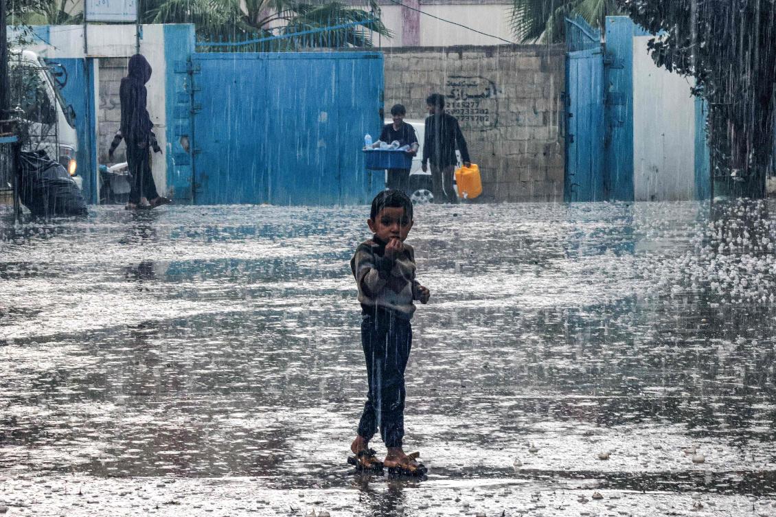 A boy stands in the rain at a school run by the United Nations Relief and Works Agency for Palestine Refugees in the Near East (UNRWA) in Rafah in the southern Gaza Strip. (AFP)