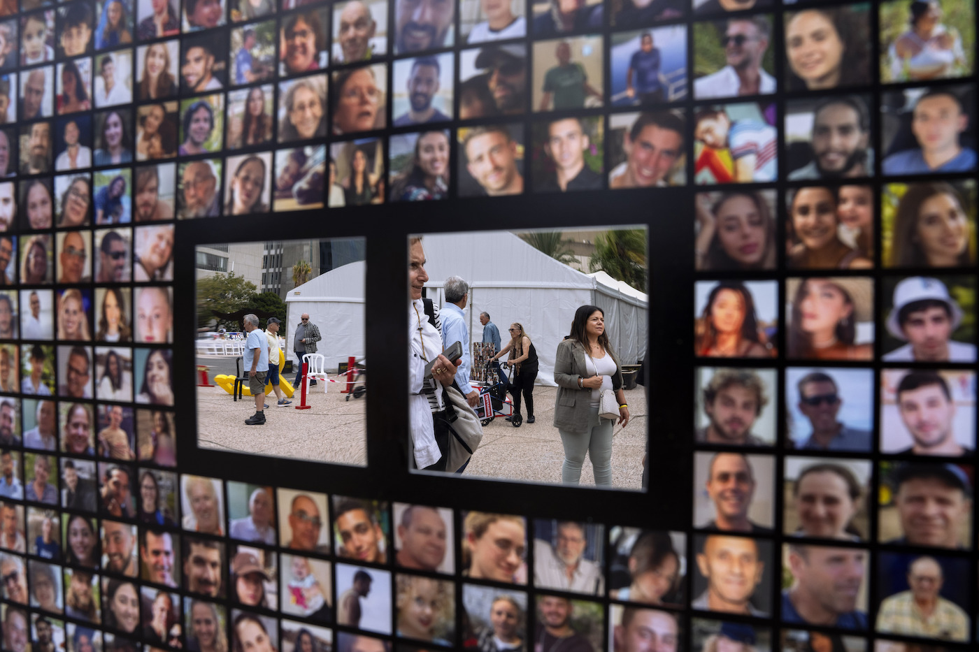 Passersby are reflected by mirrors on a poster with photographs of hostages abducted by Hamas militants in Tel Aviv, Israel, Sunday, Nov. 12, 2023. (AP)