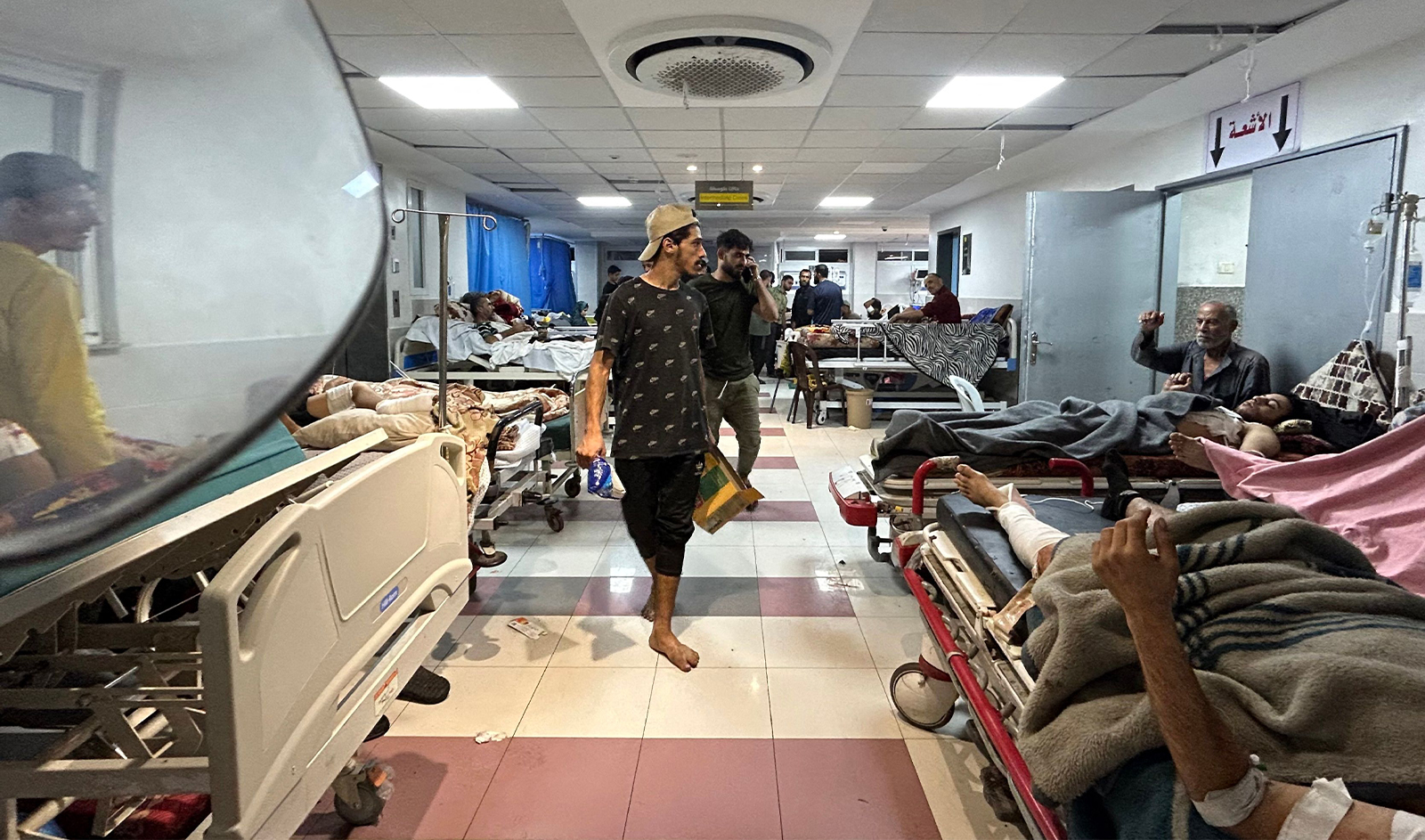 Graphic content/Men walk as patients rest at Al-Shifa hospital in Gaza City on November 10, 2023. (AFP/File)
