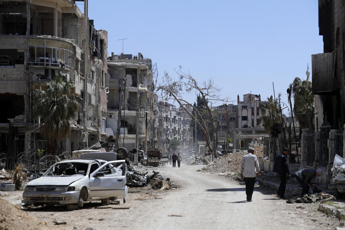 Syrians walk through destruction in the town of Douma, the site of a suspected chemical weapons attack, near Damascus on Apr. 16, 2018. (AP/File)