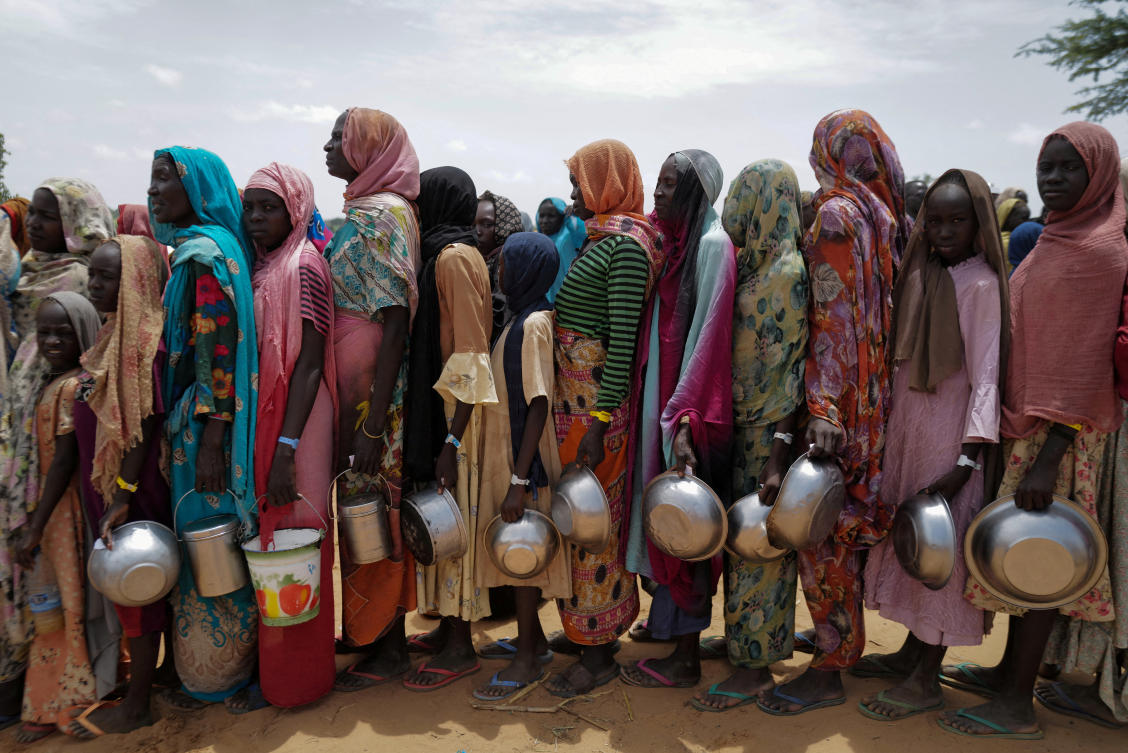 Sudanese women who fled the conflict in Geneina in Sudan’s Darfur region, line up to receive rice portions from Red Cross volunteers in Ourang on the outskirts of Adre, Chad on Jul. 25, 2023. (Reuters/File)