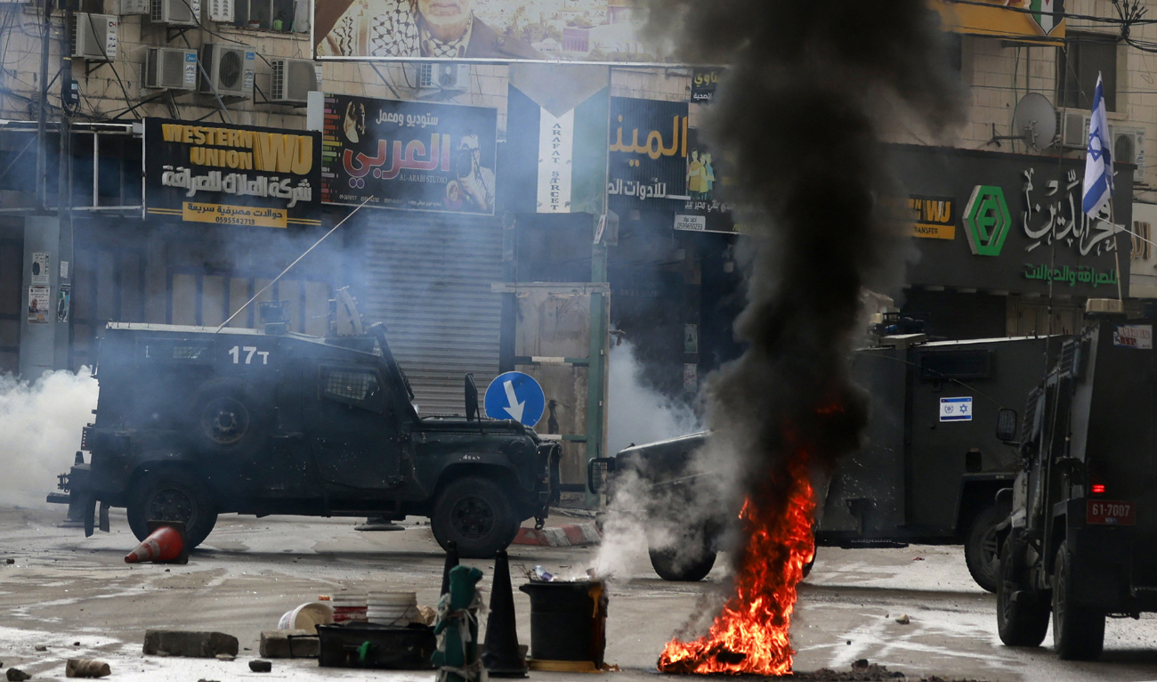 Tyres are set on fire to block Israeli army vehicles from advancing during a military operation in the occupied West Bank city of Tulkarem on November 14, 2023. (AFP)